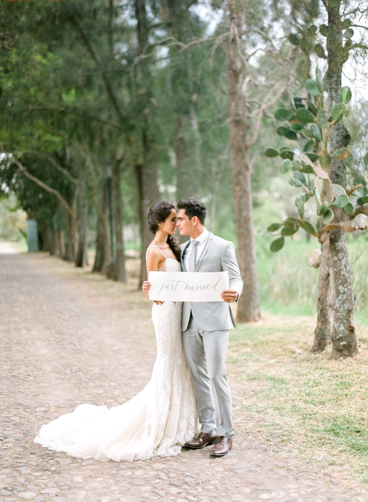 Sunset in Jalisco woods with bride and groom holding just married sign