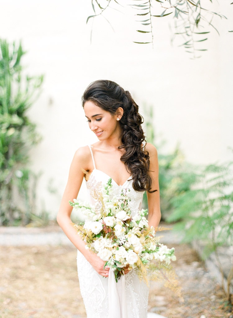 Smiling bride looking down in elegant Galia Lahav wedding gown with large assortment of white flowers