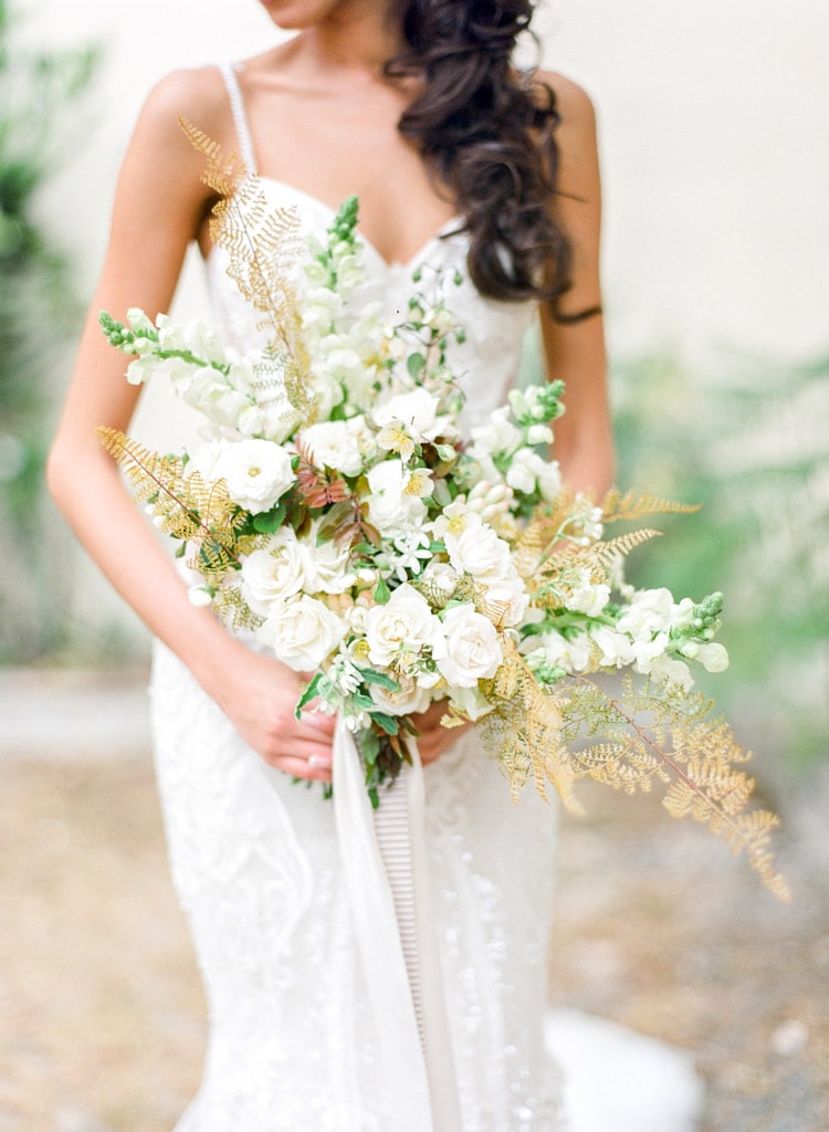 Large bouquet of flowers held by woman in white dress