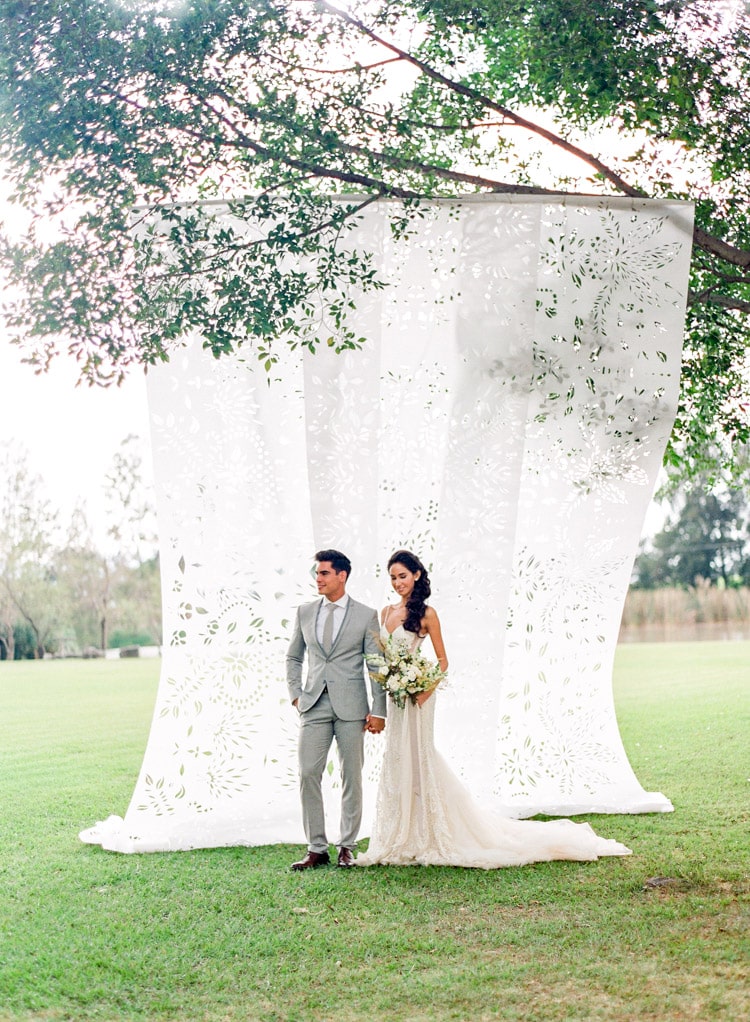 Bride and groom together holding hands with featured large white Papel Picado