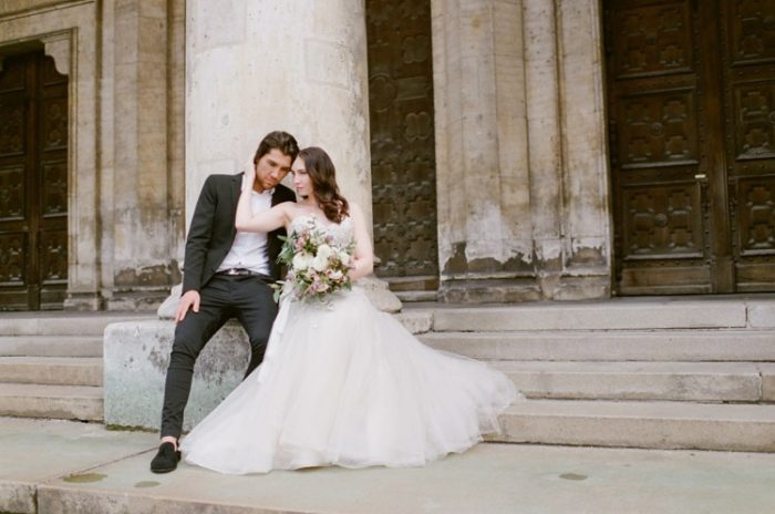 Couple sitting in front of a column at their destination wedding in France