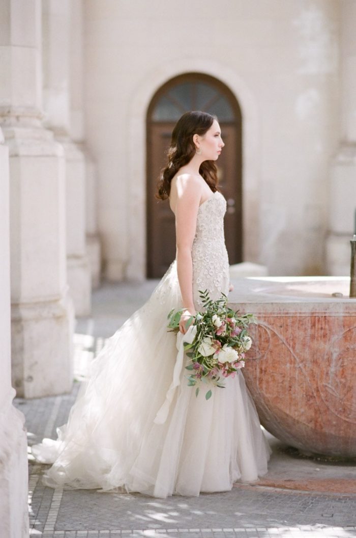 Bride holding a bouquet while standing in front of old columns in Italy