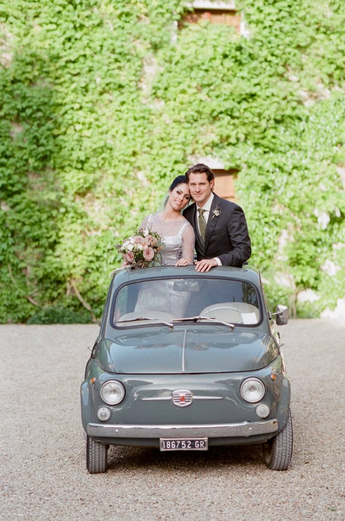 Couple in cute Italian getaway car at Borgo Pignano in Tuscany