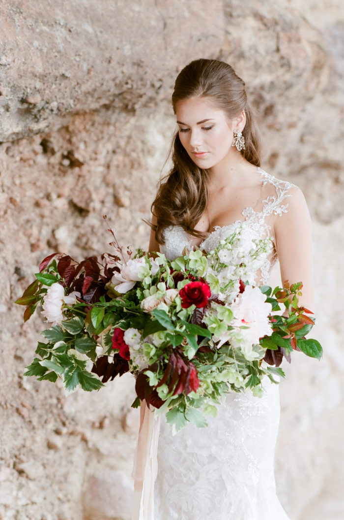 Bride holding red bouquet at Cherokee Ranch and Castle wedding in Colorado