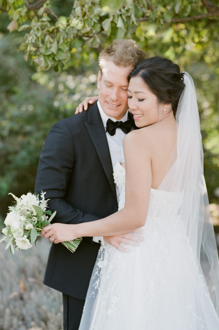 Wedding couple holding each other closely while posing for wedding portrait