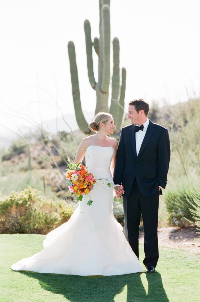 Newlywed couple standing in front of a cactus at Desert Mountain Golf Course in Scottsdale