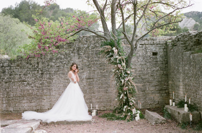 Bride standing in front of a stone wall at Domaine de Manville in France