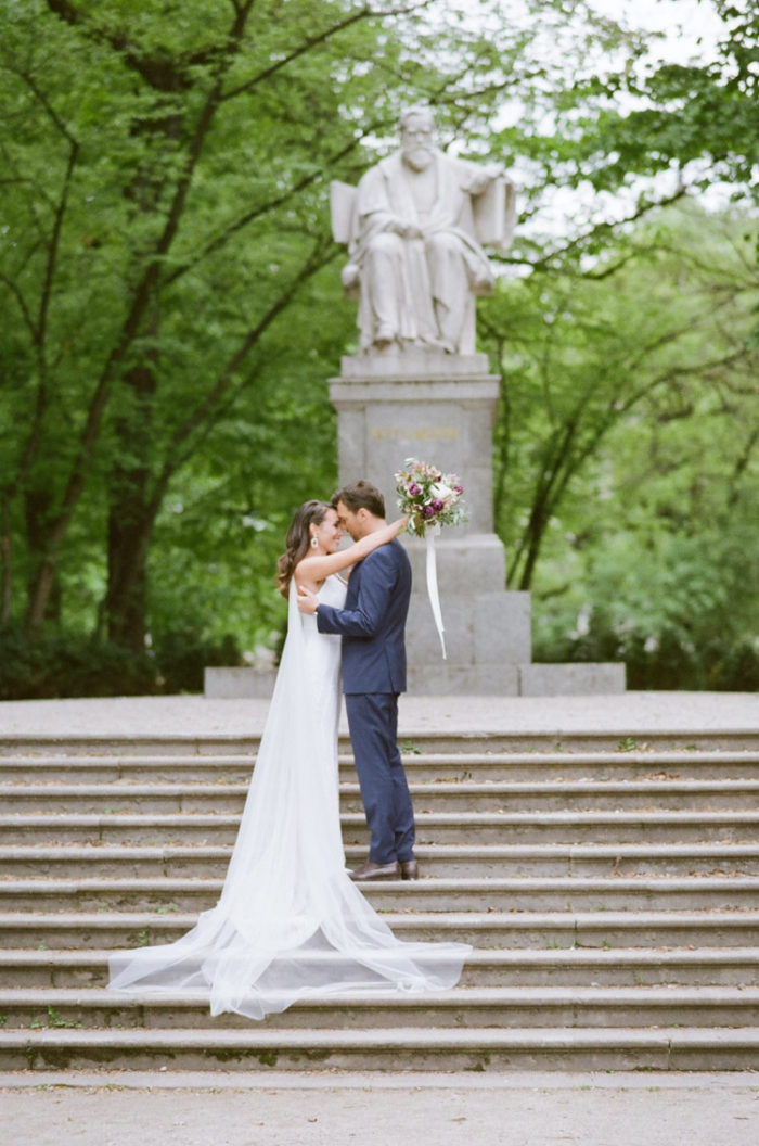 Couple embracing on stone steps in front of a statue at their destination wedding
