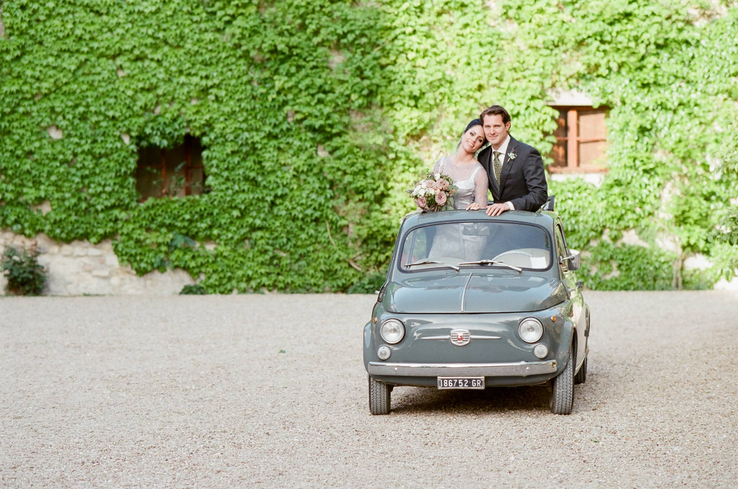 Bride and groom in an old timer Cinquecento at Borgo Pignano in Tuscany Italy