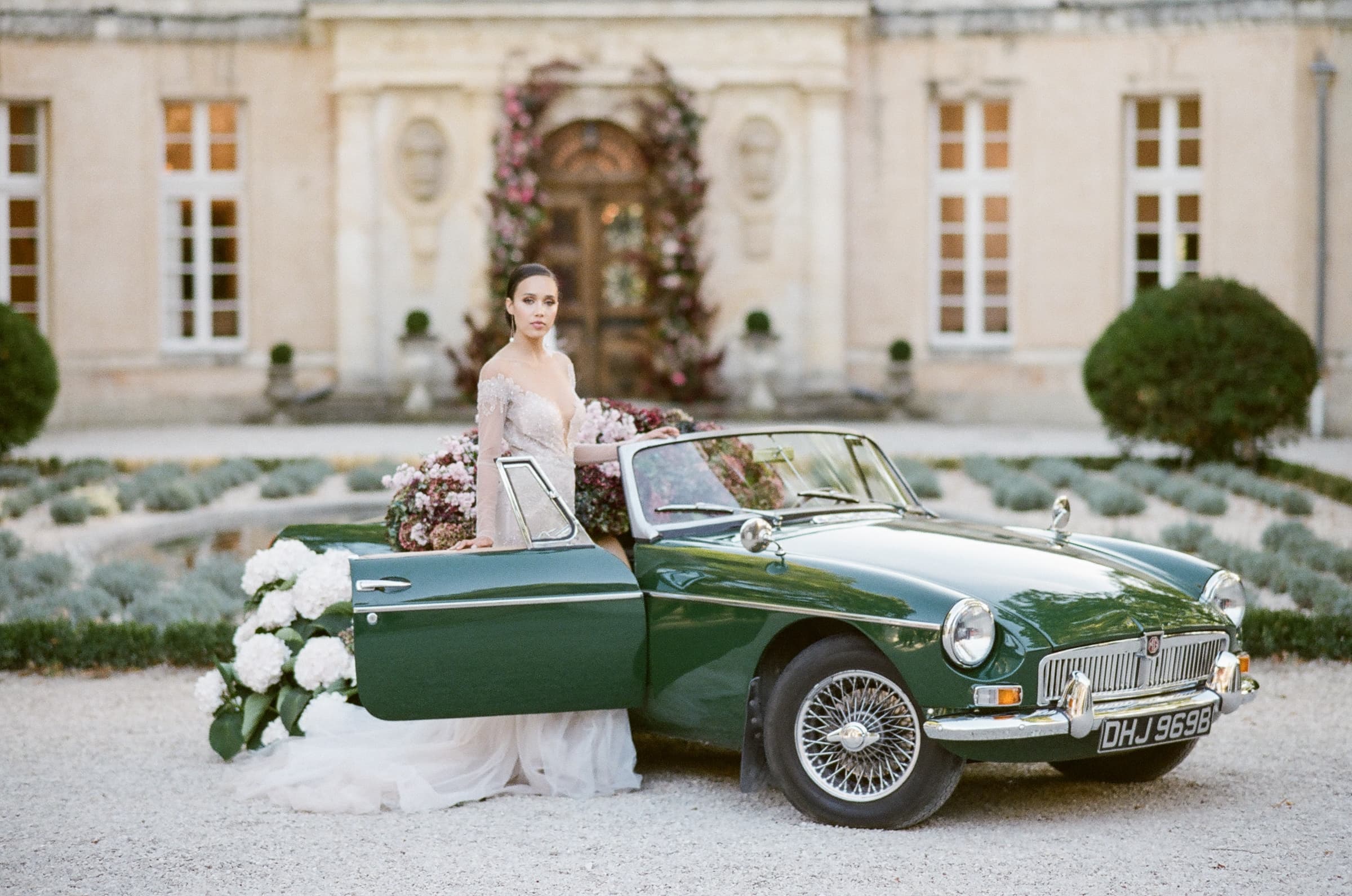 Bride in her blush Berta wedding gown standing next to her green old timer in front of Chateau Martinay in Provence