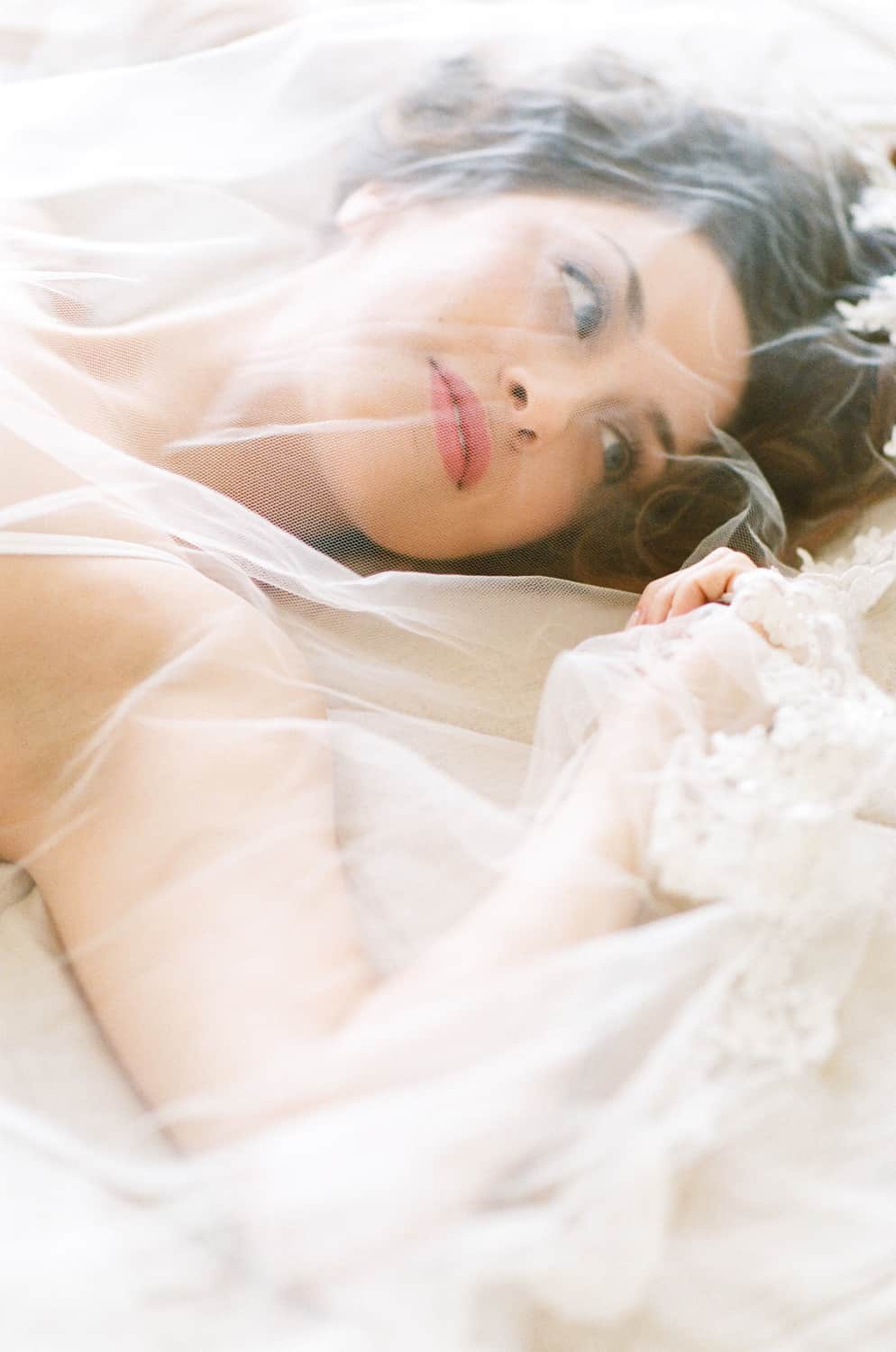 Bride with veil in bed during Denver boudoir portrait session
