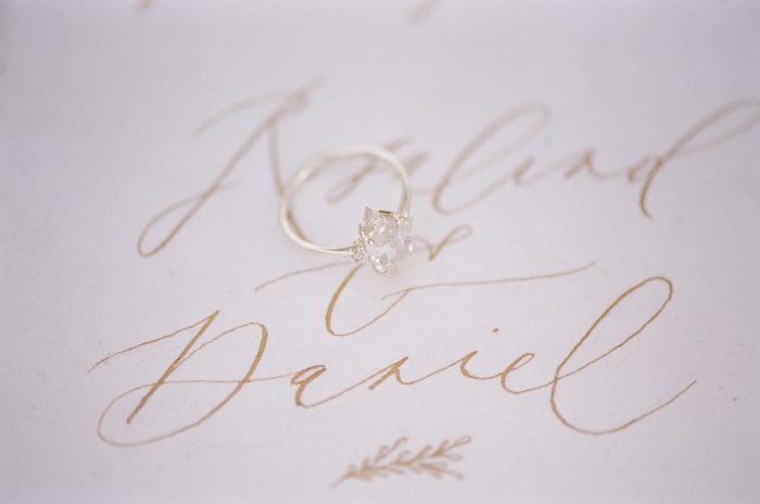 Detail shot taken while couple was getting ready of an engagement ring sitting on a wedding invitation