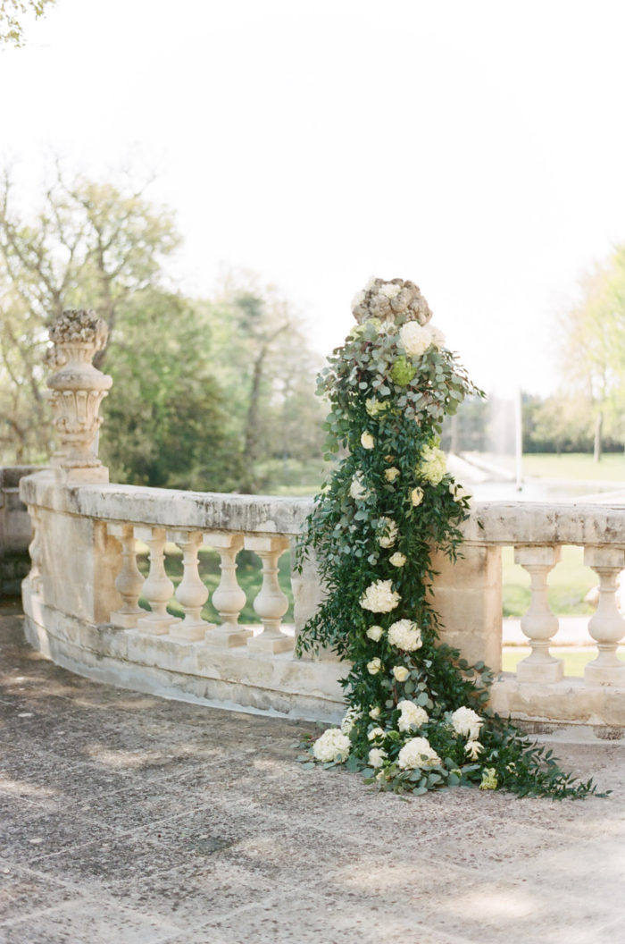 Elegant stone railing covered in floral and greenery at Chateau de Tourreau
