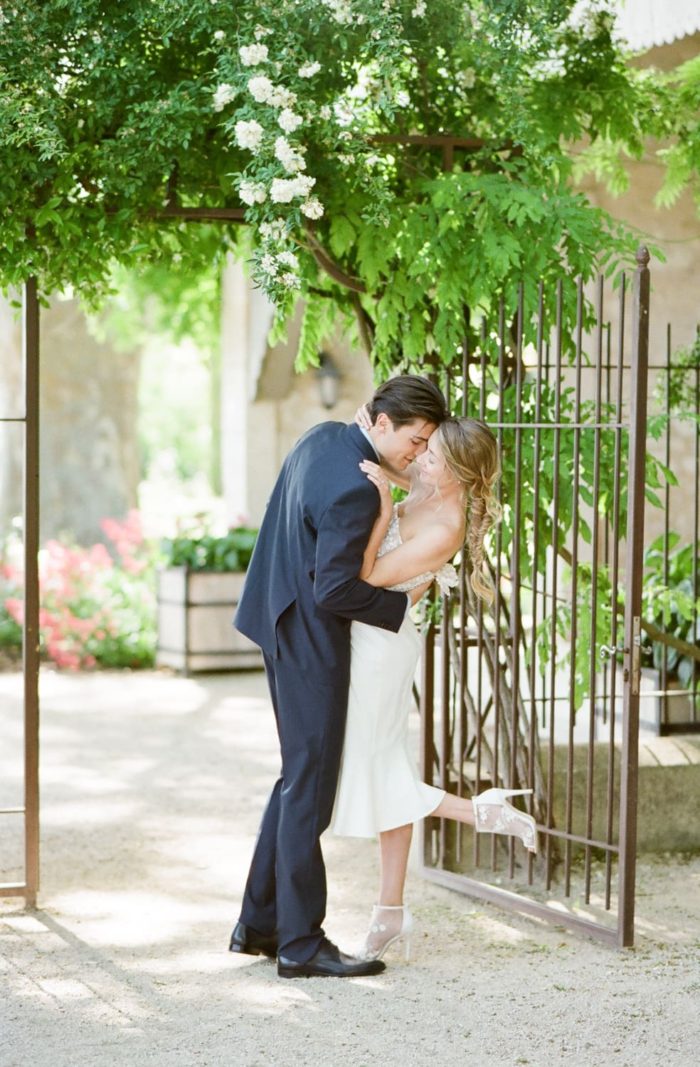 Couple kissing in front of an iron gate in Provence