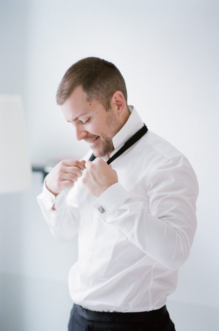Groom tying his bowtie at the Halcyon Hotel in Denver