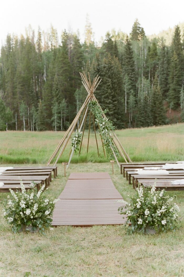 A modern teepee serves as a wedding ceremony backdrop at an outdoor wedding in Vail Colorado at Eaton Ranch