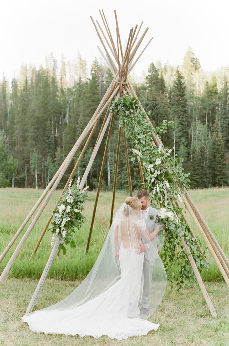 Couple standing in front of a teepee structure at an outdoor wedding in Vail Colorado at Eaton Ranch