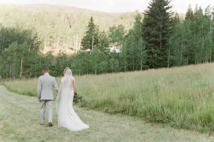Couple holding hands and walking through a field at Eaton Ranch in Vail