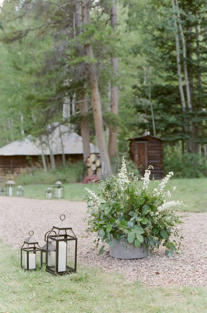 White floral arrangement and two lanterns serve as wedding decor at an outdoor wedding in Vail Colorado