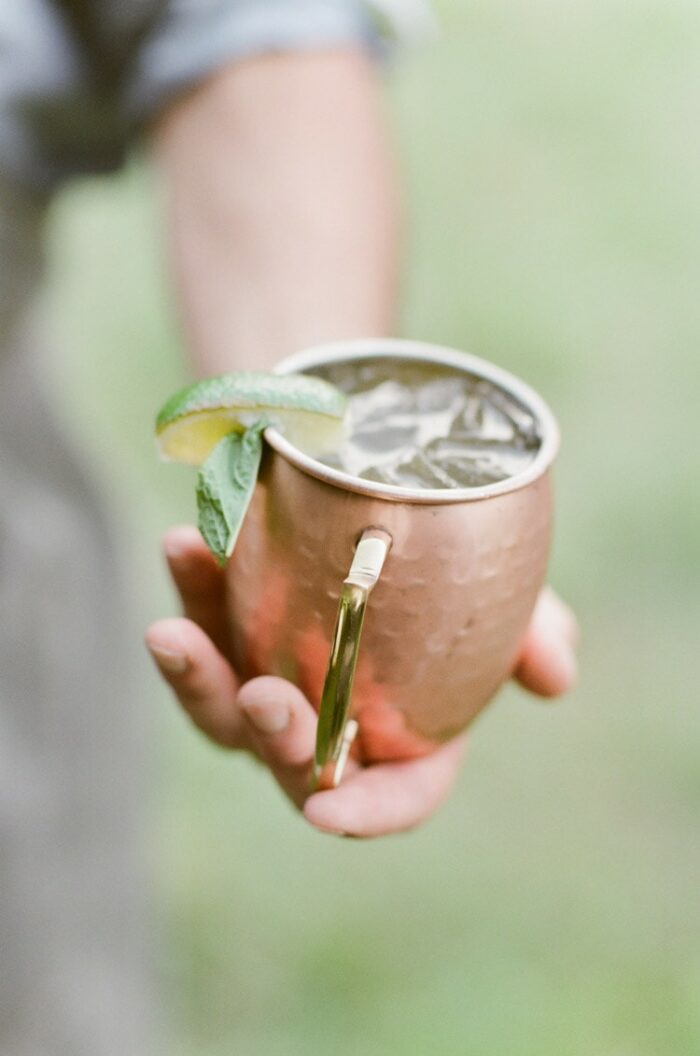 Hand holding a Moscow Mule drink in a copper mug