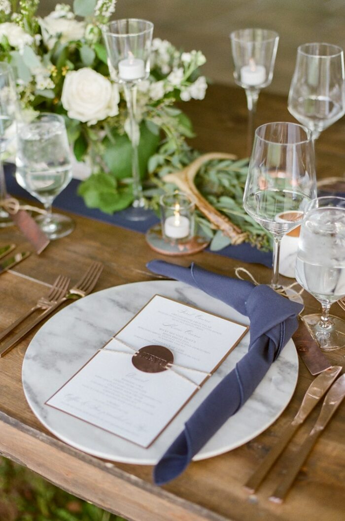 Rustic floral arrangement and place setting at a tented wedding reception in Vail Colorado