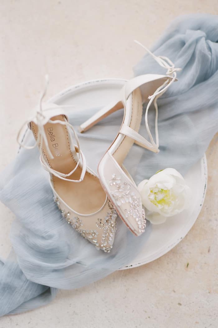 Bella Belle Shoes laying on top of blue mesh and next to white flower