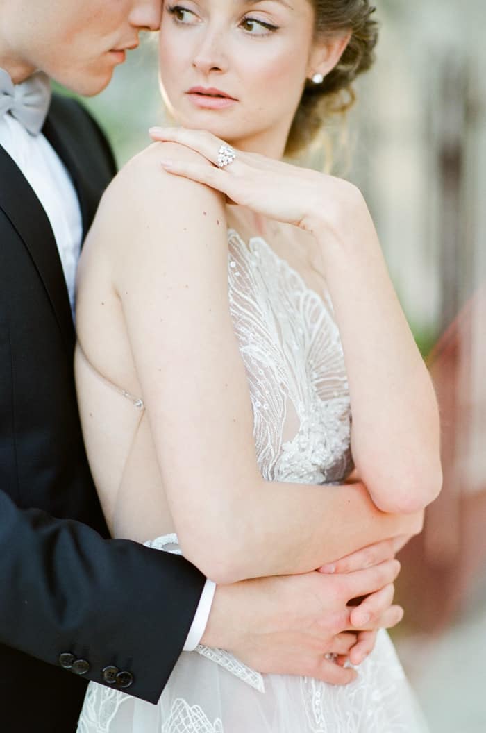Romance of bride being embraced from behind by groom