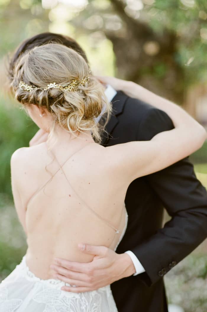 Woman wearing backless wedding dress embracing partner