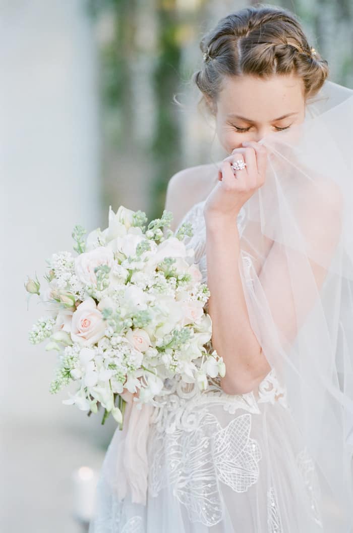 Bride posing and hiding face behind wedding veil