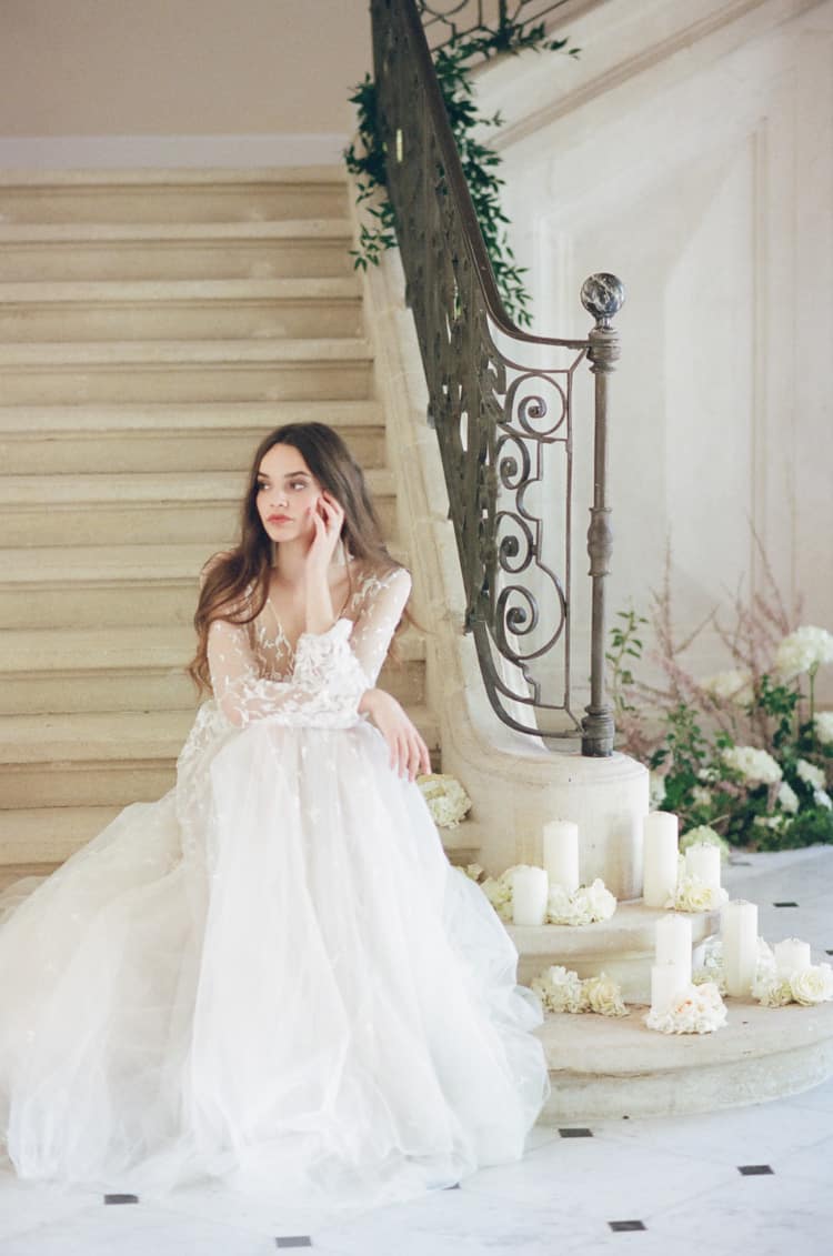 Bride in her lace dress sitting at the staircase at Chateau de Tourreau in Provence