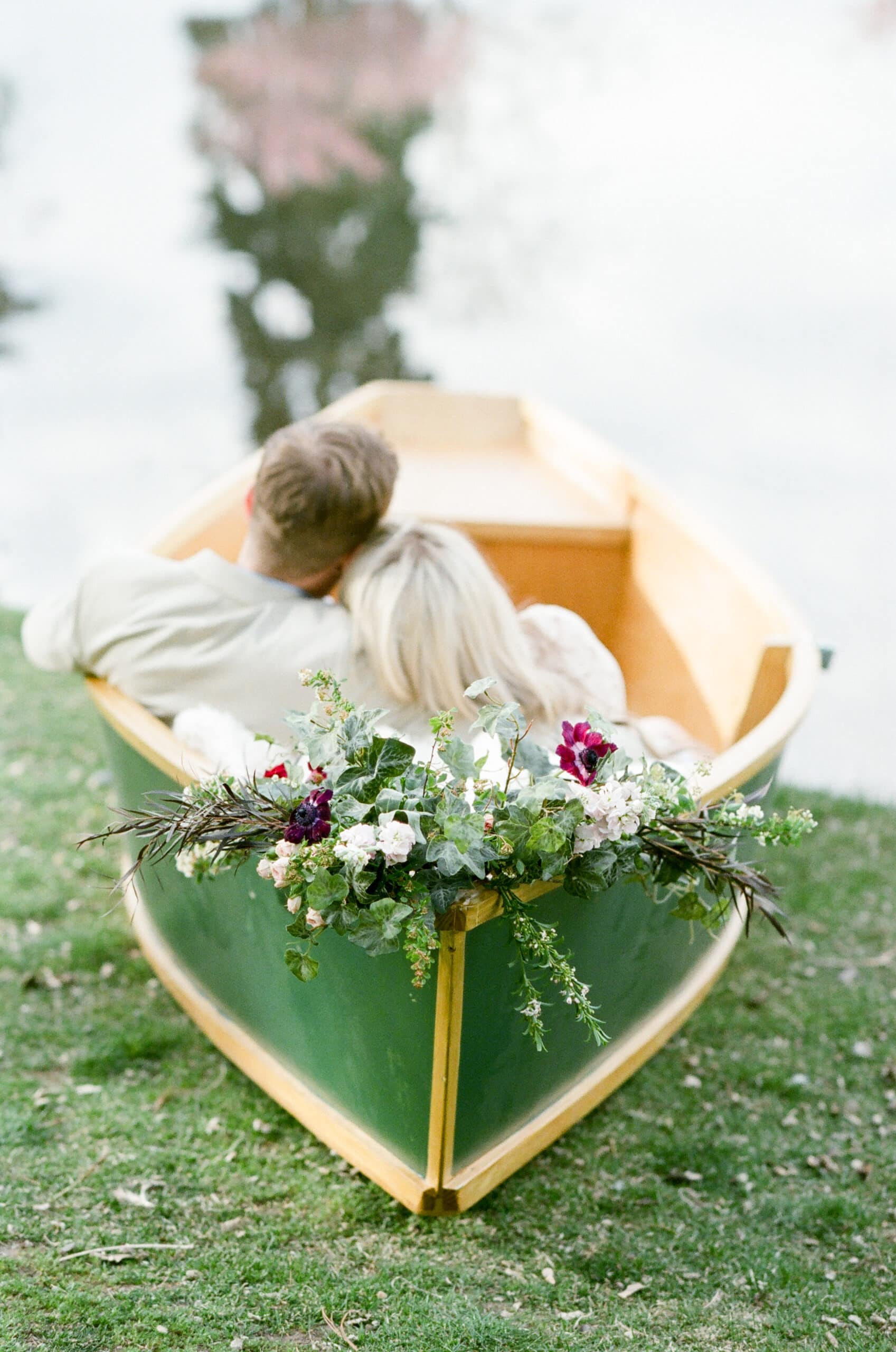 Engaged couple sitting in a green wood boat embracing each other in Denver Colorado