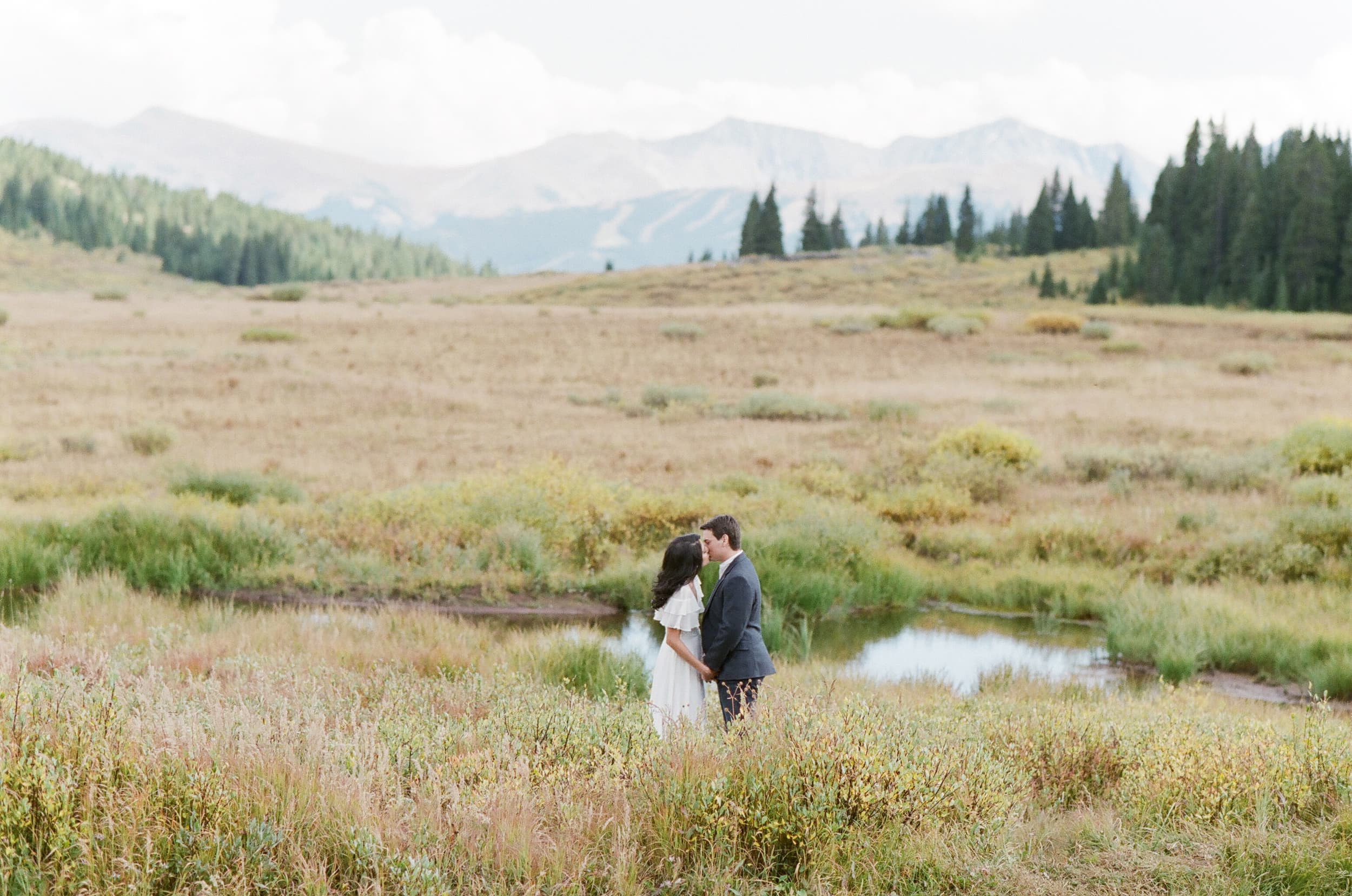 Engaged couple in the fields in front of Vail mountain in Colorado