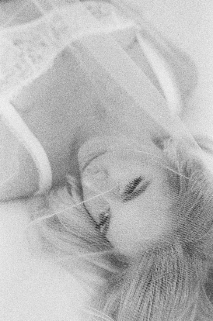 Bride covered in her veil in bed