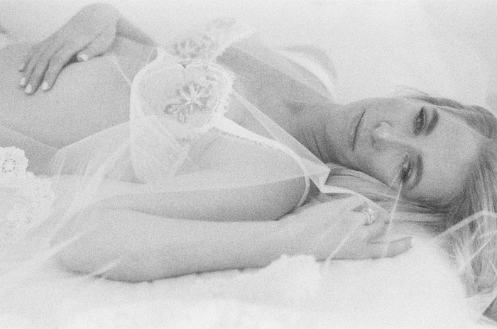 Closeup of bride in her white lingerie covered by her veil