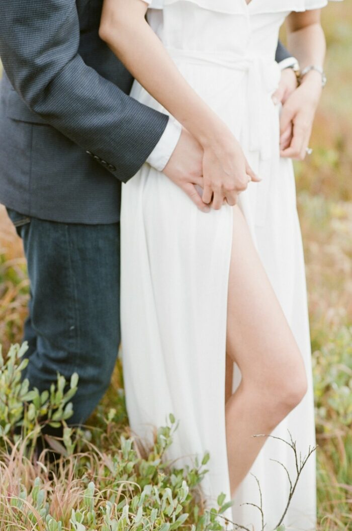 Lower view of couple's legs wearing jeans and white skirt