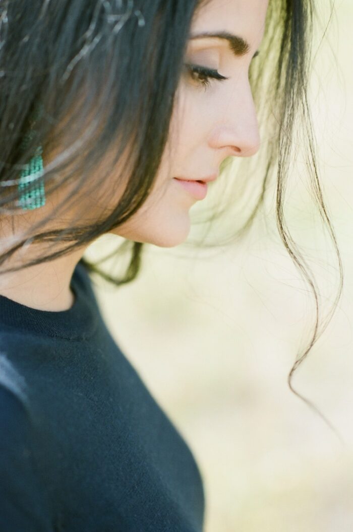 Close up of woman wearing navy sweater and turquoise earrings