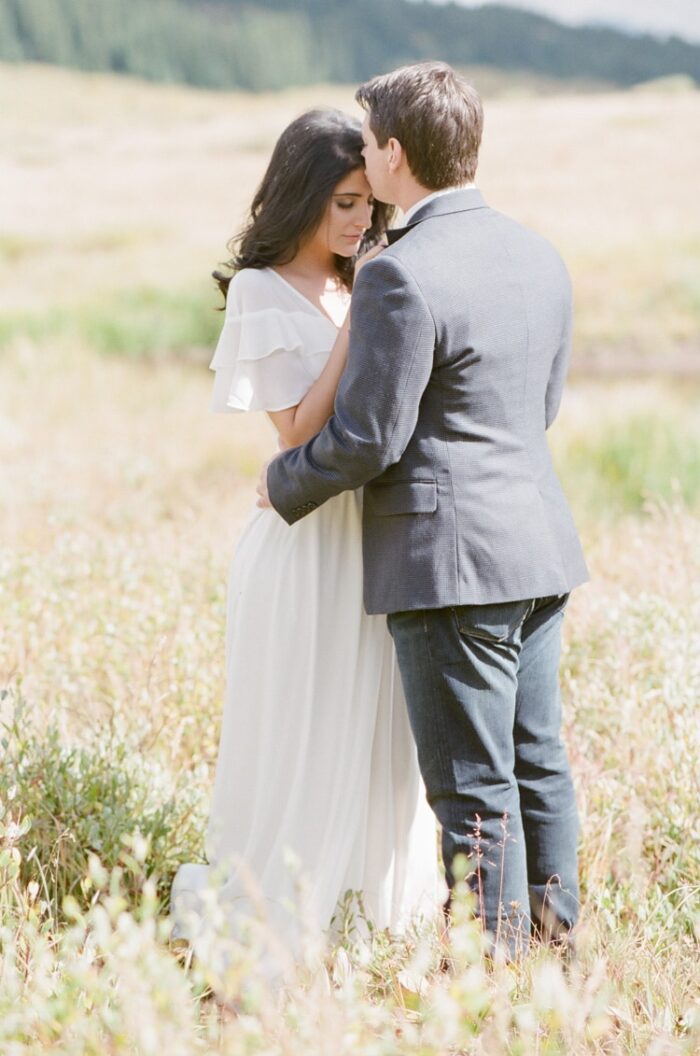 Colorado engagement session with couple wearing soft colored tones embracing each other