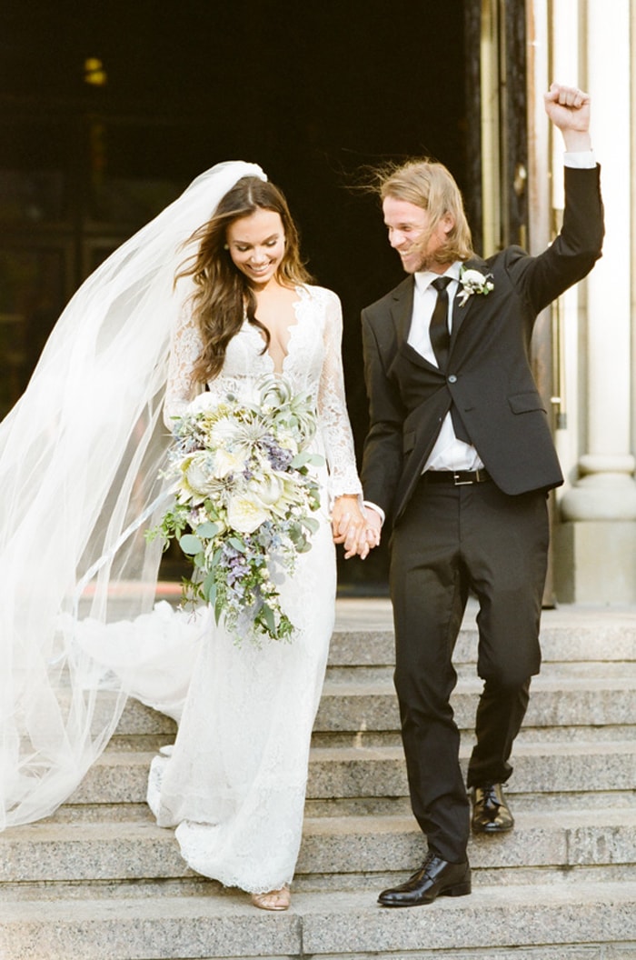 Bride and groom wearing Prada suit just married walking down stairs
