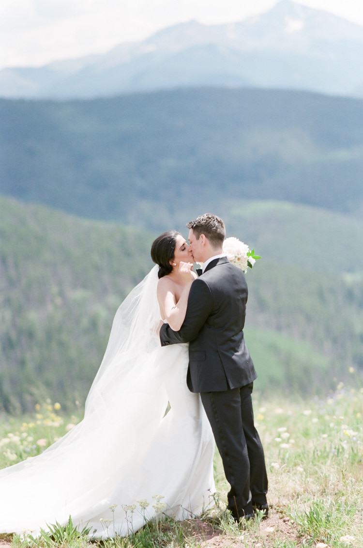 Wedding couple getting their first look at each other and kissing with scenic mountain view