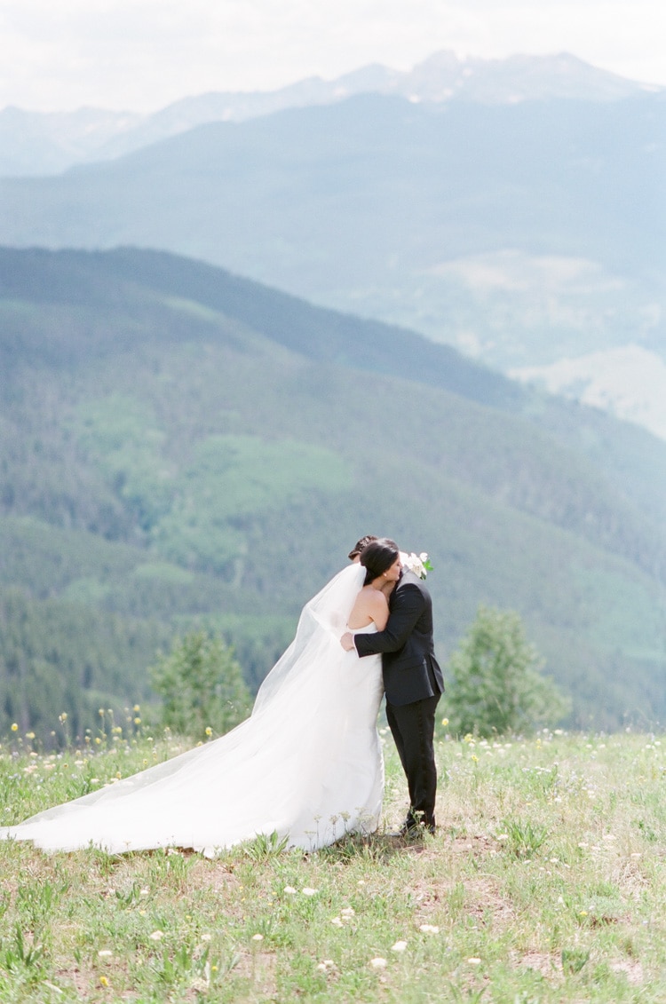 Bride and groom on wedding day embracing with backdrop of the mountains