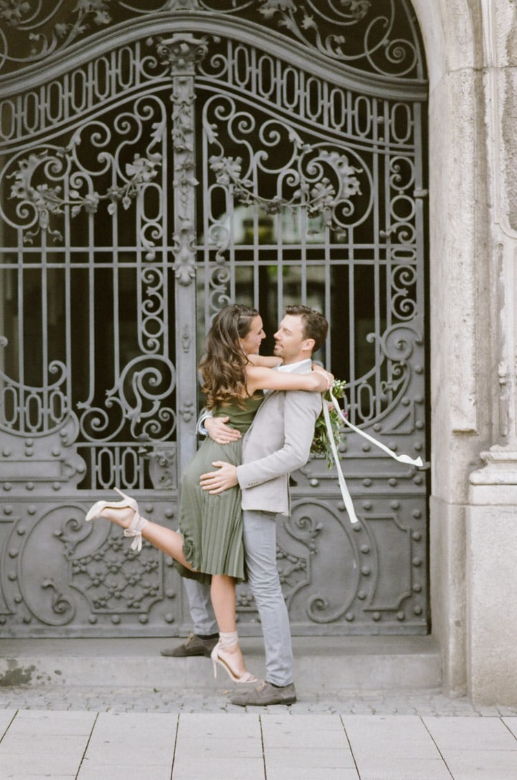Man holding his fiance in front of an iron gate in Munich