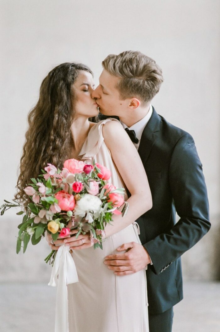 Couple kissing while woman holds a pink bouquet