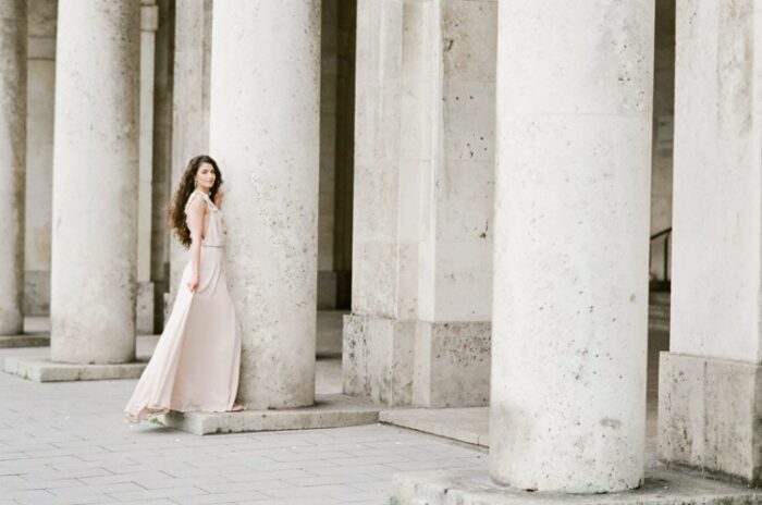 Woman in pink gown standing in front of columns in Munich