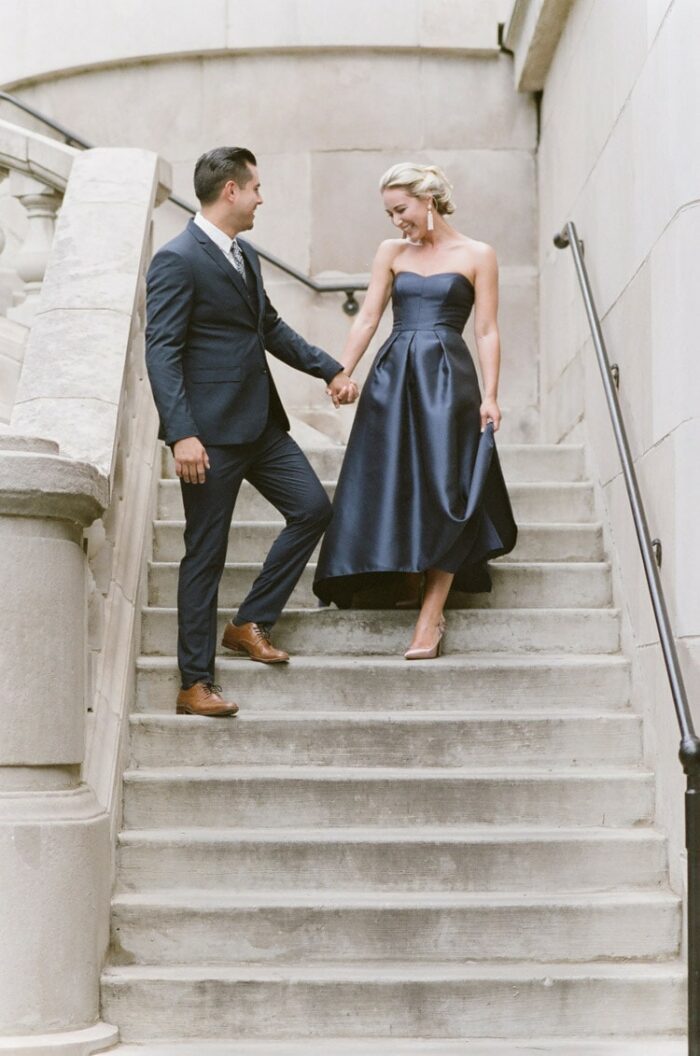 Engagement couple walking down outside stairs holding hands