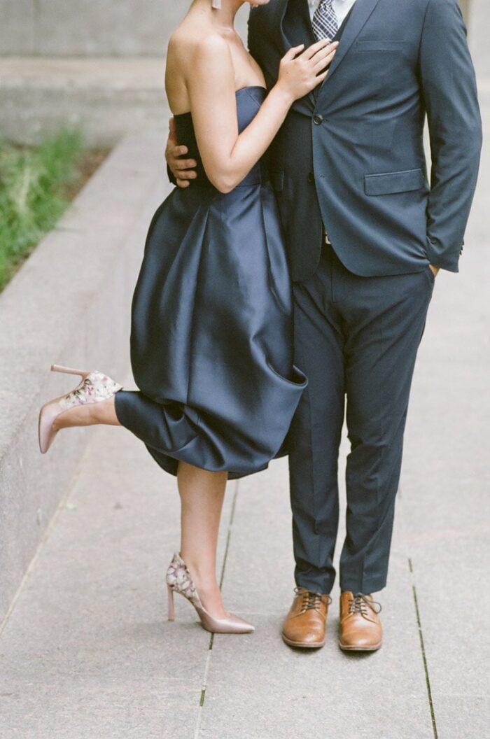 Couple's navy blue outfits with blush high-heels and tan dress shoes