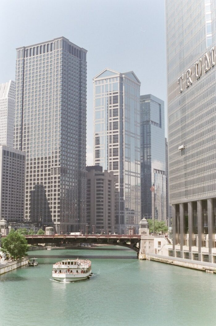 Chicago Riverwalk with ferry boat on the river going under a bridge with skyscrapers in the background