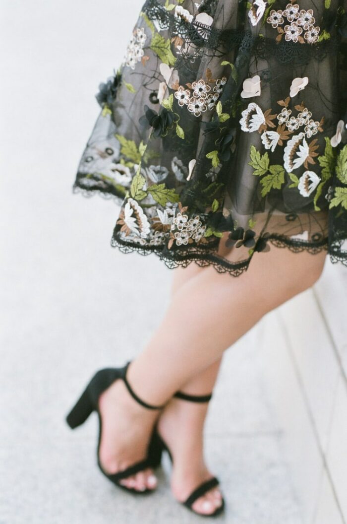 Bottom half of black mini dress with colorful floral embroidery and black heels