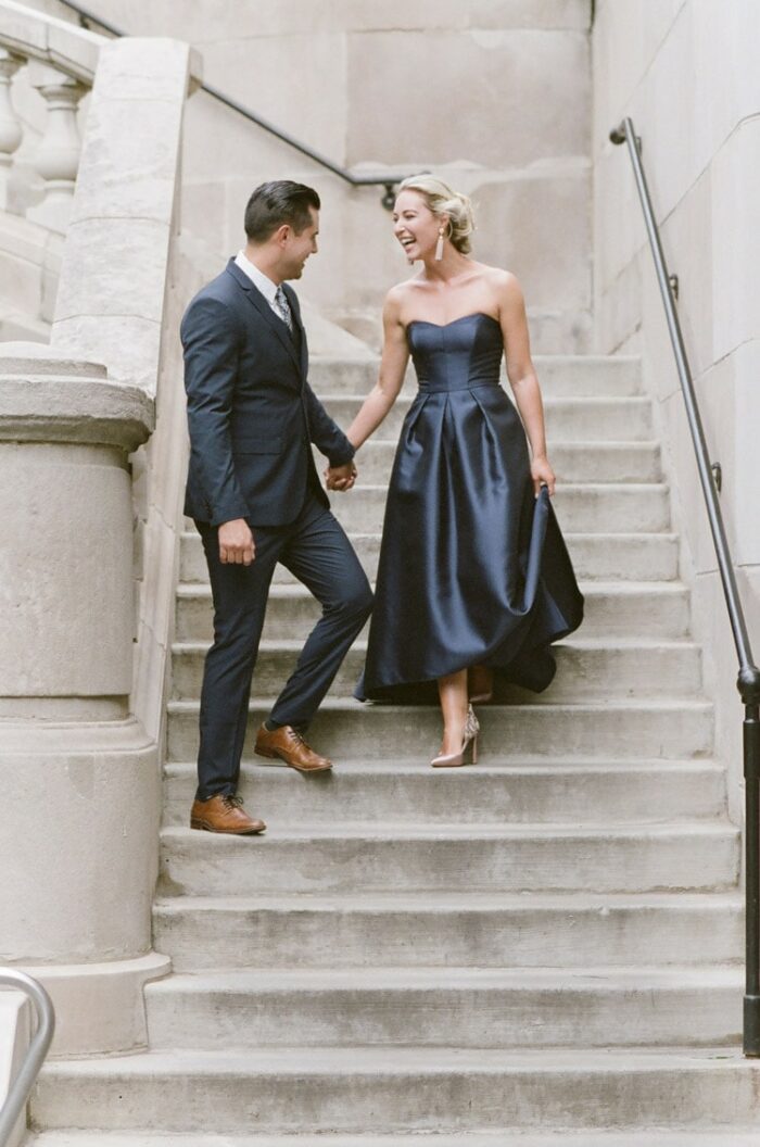 Engagement couple walking down outside stairs holding hands