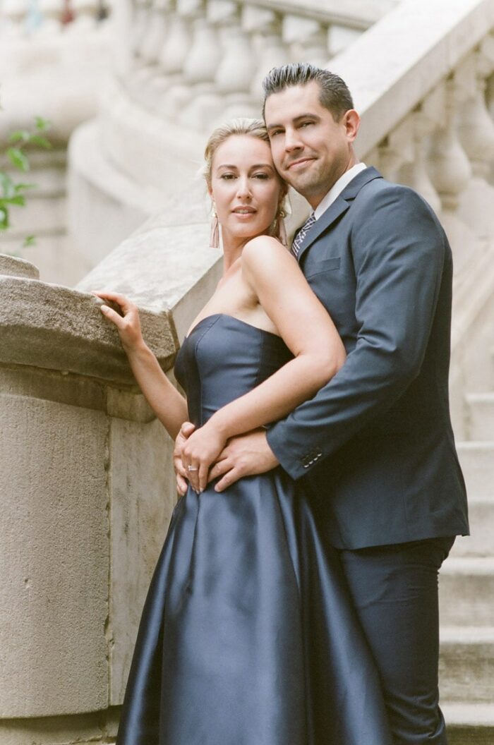 Couple in navy blue colored outfits outside next to stairs