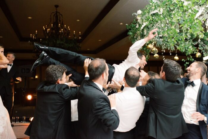 Groom being lifted up by people at reception